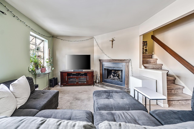 living room featuring carpet flooring, a fireplace, and stairway