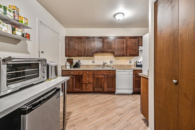 kitchen with light countertops, a sink, white dishwasher, light wood-type flooring, and dishwasher