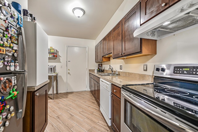 kitchen with under cabinet range hood, stainless steel appliances, a sink, light wood-style floors, and light countertops