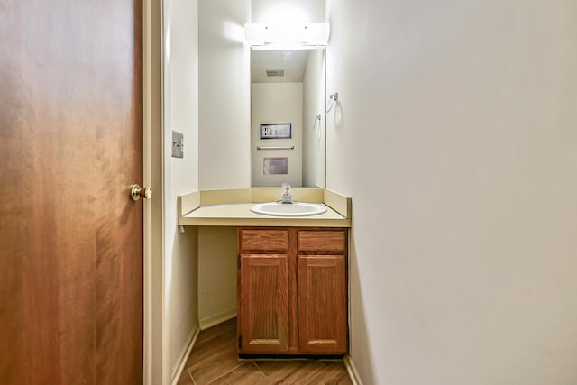 bathroom with baseboards, visible vents, wood finished floors, and vanity