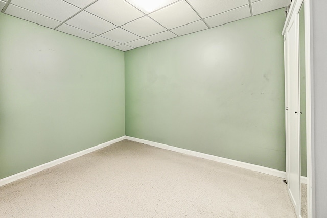 empty room featuring baseboards and a drop ceiling