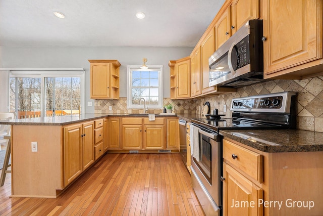 kitchen featuring light brown cabinetry, sink, a breakfast bar area, dark stone counters, and stainless steel appliances