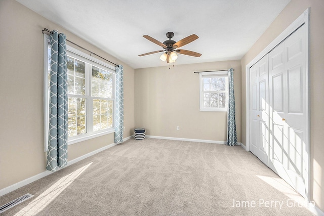 unfurnished bedroom with ceiling fan, carpet flooring, a closet, and multiple windows