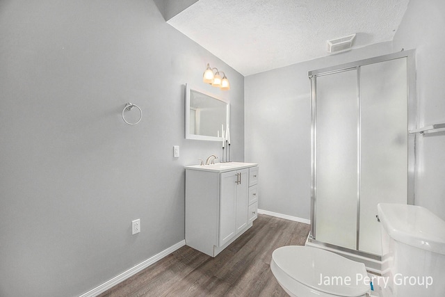 bathroom featuring hardwood / wood-style floors, vanity, toilet, a shower with door, and a textured ceiling