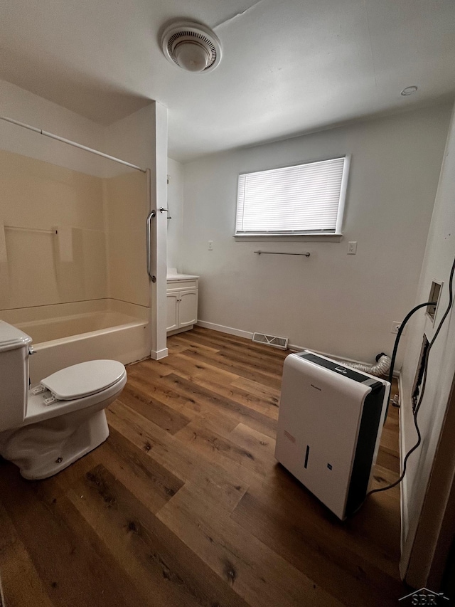 full bathroom with hardwood / wood-style flooring, shower / bathtub combination, vanity, and toilet