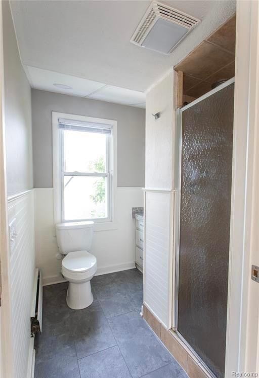 bathroom featuring walk in shower, toilet, vanity, tile patterned flooring, and a baseboard heating unit