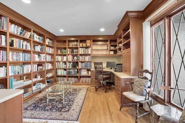 home office featuring recessed lighting, bookshelves, built in desk, and light wood finished floors