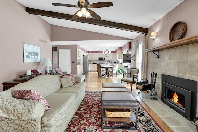 living room with vaulted ceiling with beams, a fireplace, visible vents, light tile patterned flooring, and ceiling fan with notable chandelier