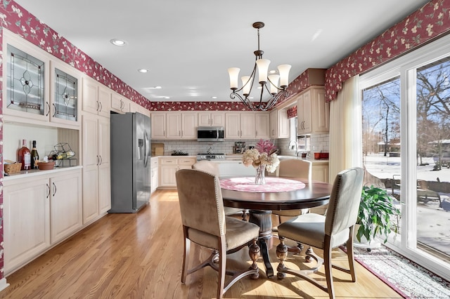 dining space with wallpapered walls, recessed lighting, light wood finished floors, and an inviting chandelier