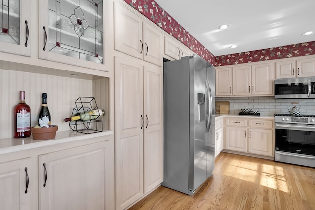 kitchen featuring wallpapered walls, light wood-style flooring, stainless steel appliances, and light countertops