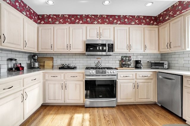 kitchen with light wood finished floors, a toaster, stainless steel appliances, and light countertops