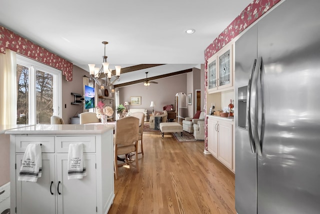 kitchen featuring stainless steel fridge with ice dispenser, open floor plan, light countertops, light wood-style floors, and white cabinetry