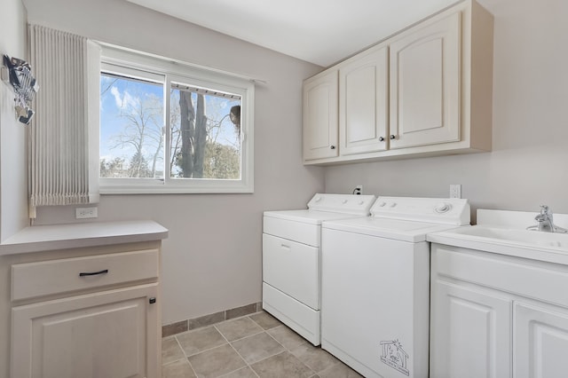 clothes washing area with washing machine and clothes dryer, light tile patterned floors, cabinet space, a sink, and baseboards