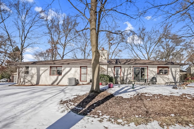 view of front of house featuring a chimney, cooling unit, and brick siding