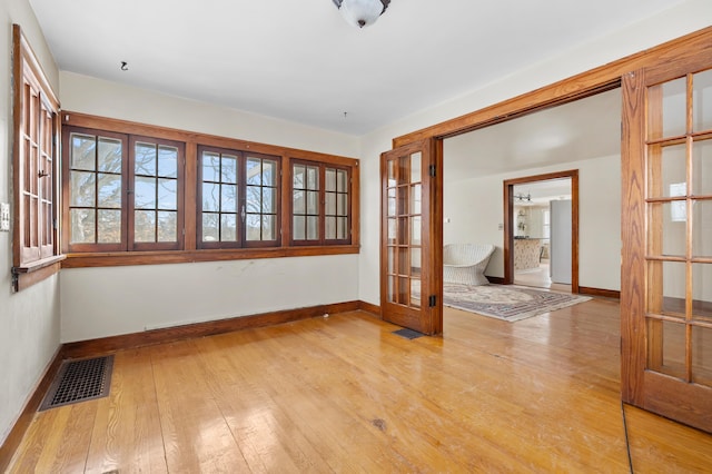 spare room featuring french doors and light hardwood / wood-style flooring