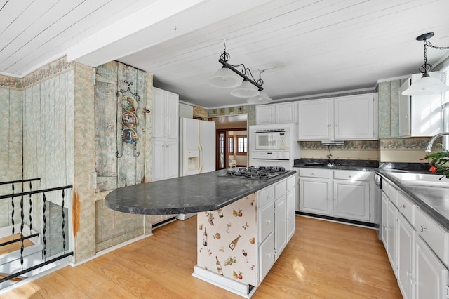 kitchen with a kitchen island, white cabinetry, hanging light fixtures, light hardwood / wood-style floors, and white appliances