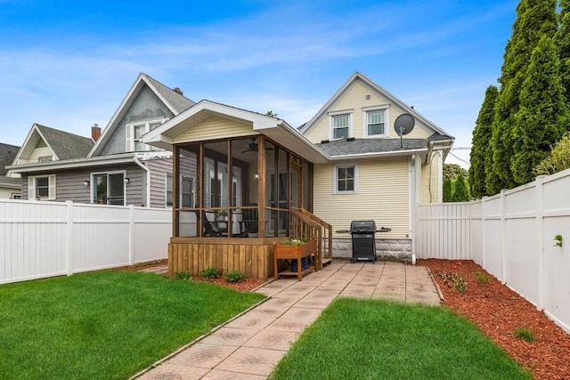 back of house with a lawn, a sunroom, and ceiling fan