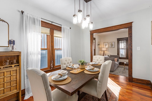 dining area featuring wood-type flooring, a wealth of natural light, and an inviting chandelier