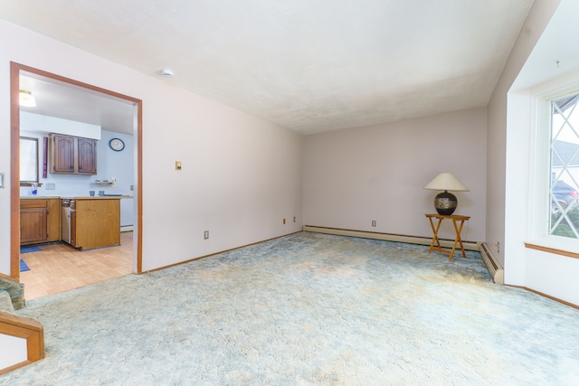 spare room featuring baseboards, baseboard heating, and light colored carpet