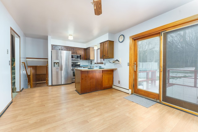 kitchen with a baseboard radiator, appliances with stainless steel finishes, a peninsula, light countertops, and light wood-style floors