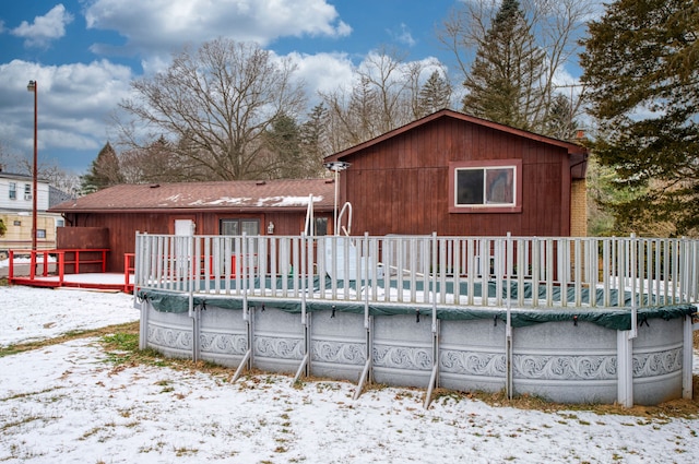 snow covered property featuring a covered pool and a wooden deck