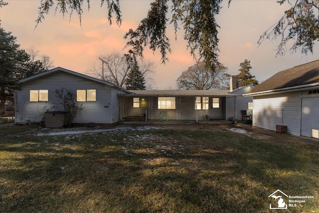 back house at dusk featuring a yard