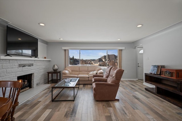 living room featuring hardwood / wood-style floors and a stone fireplace