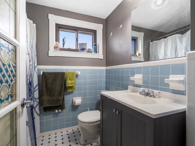 bathroom featuring vanity, tile walls, and toilet