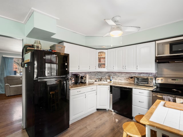 kitchen with white cabinetry, backsplash, black appliances, and sink