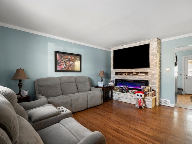 living room featuring a fireplace, crown molding, and wood-type flooring