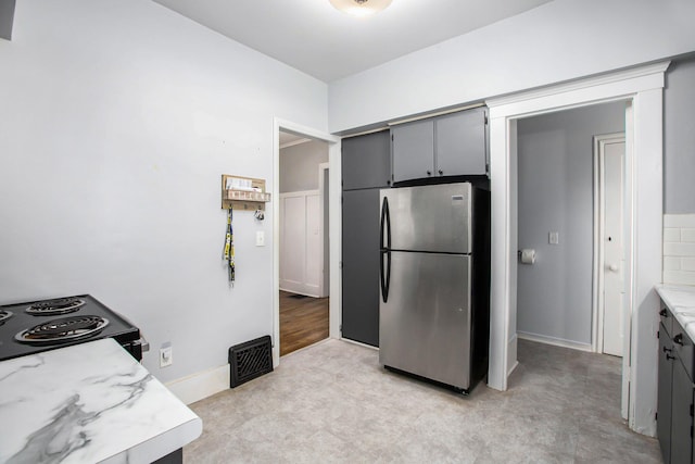 kitchen featuring gray cabinetry, black electric range oven, and stainless steel refrigerator