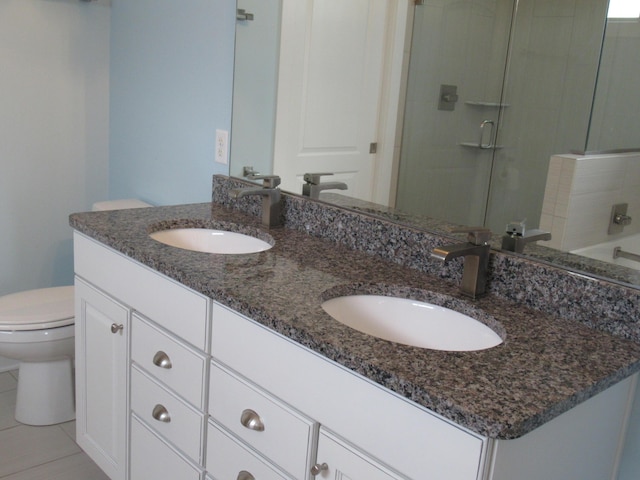 full bathroom featuring a sink, a shower stall, toilet, and double vanity