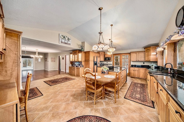 dining space featuring an inviting chandelier, sink, vaulted ceiling, and a textured ceiling