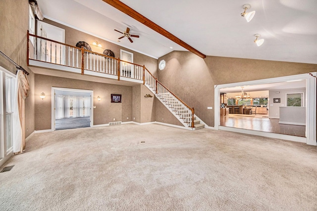 unfurnished living room featuring ceiling fan with notable chandelier, carpet flooring, high vaulted ceiling, and beam ceiling