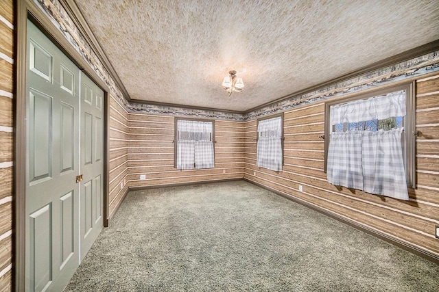 spare room featuring crown molding, a textured ceiling, and carpet