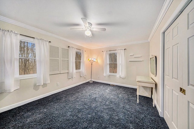 spare room featuring ceiling fan, crown molding, a healthy amount of sunlight, and dark colored carpet