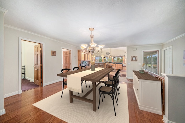 dining space featuring wood-type flooring, ornamental molding, and a chandelier