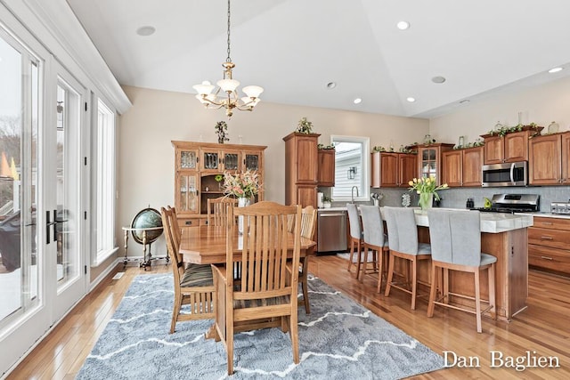 dining space featuring lofted ceiling, sink, a chandelier, and light hardwood / wood-style flooring