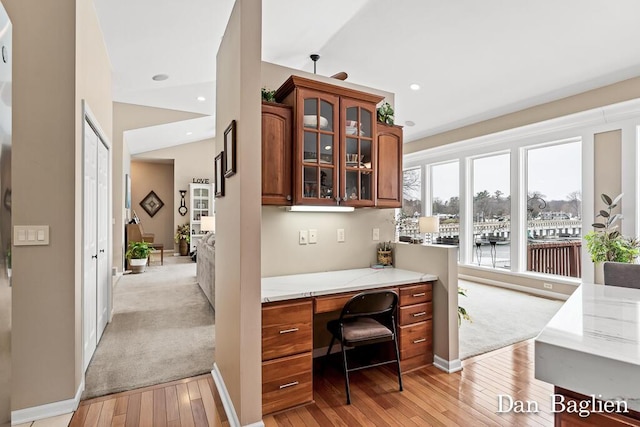 office with lofted ceiling, built in desk, and light hardwood / wood-style flooring