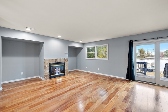 unfurnished living room featuring a water view and light hardwood / wood-style flooring