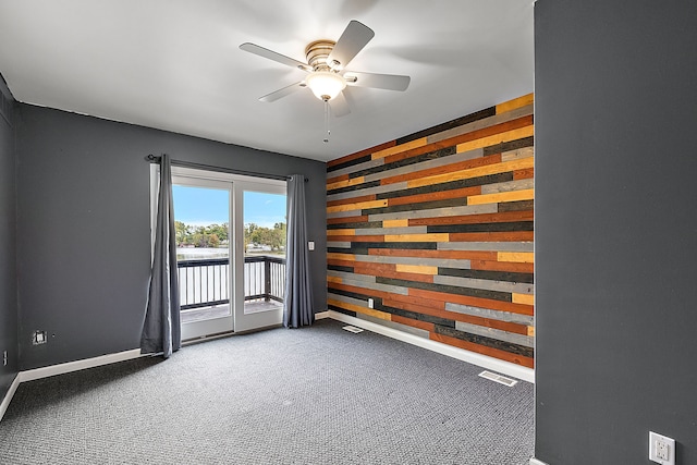 spare room featuring ceiling fan, carpet flooring, and wooden walls