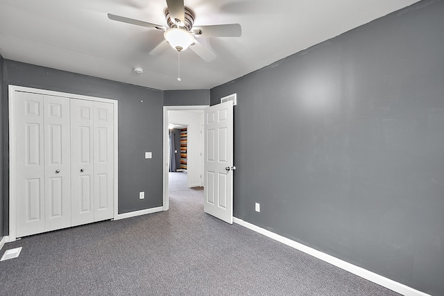 unfurnished bedroom with dark carpet, ceiling fan, and a closet