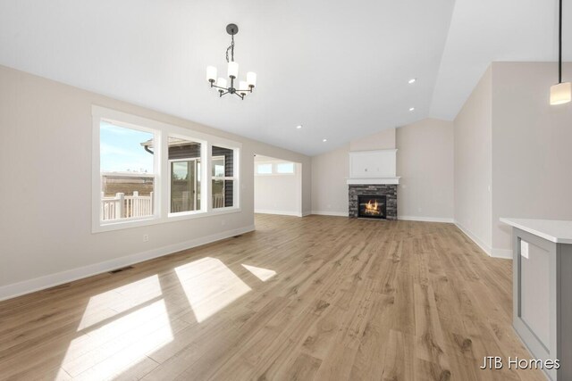 3432 Conrail Dr, Byron Center, MI 49315 - unfurnished living room featuring a chandelier, light wood-type flooring, a fireplace, vaulted ceiling, and baseboards