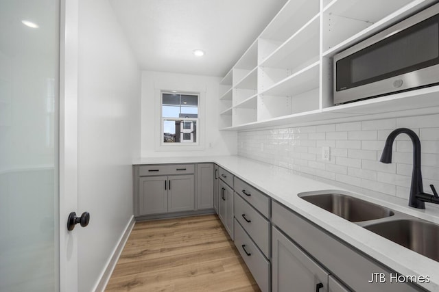 3432 Conrail Dr, Byron Center, MI 49315 - kitchen featuring gray cabinets, a sink, stainless steel microwave, open shelves, and backsplash