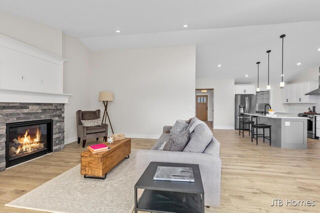 3432 Conrail Dr, Byron Center, MI 49315 - living room featuring lofted ceiling, a stone fireplace, light wood-type flooring, baseboards, and recessed lighting