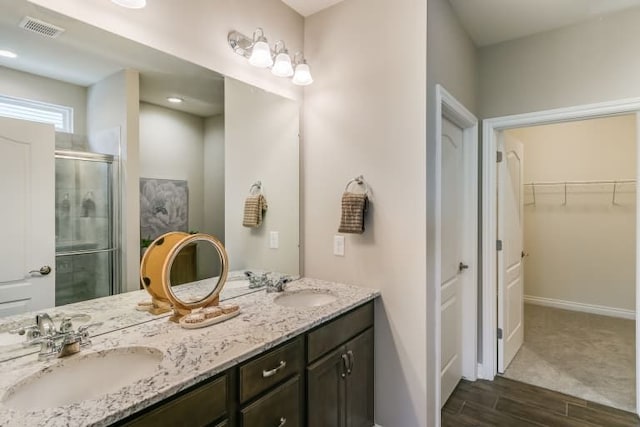 bathroom featuring a shower with door and vanity