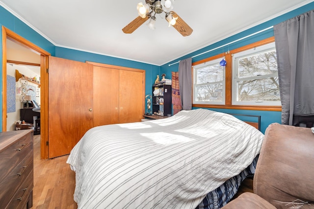 bedroom with crown molding, light hardwood / wood-style floors, a closet, and ceiling fan