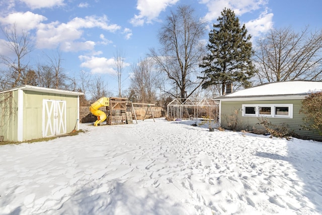 snowy yard with a playground and a storage unit