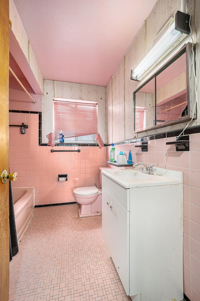 bathroom featuring vanity, toilet, tile walls, and a tub to relax in