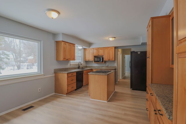 kitchen with light wood-type flooring, a center island, sink, and black appliances